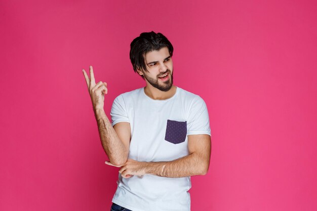 Man in white shirt making peace hand sign and sending message.