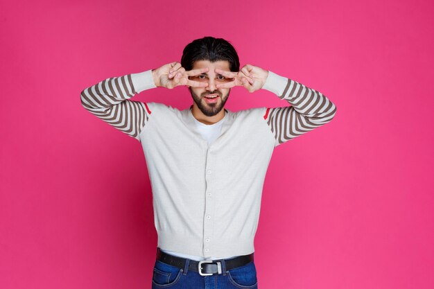 Man in a white shirt making peace sign. 