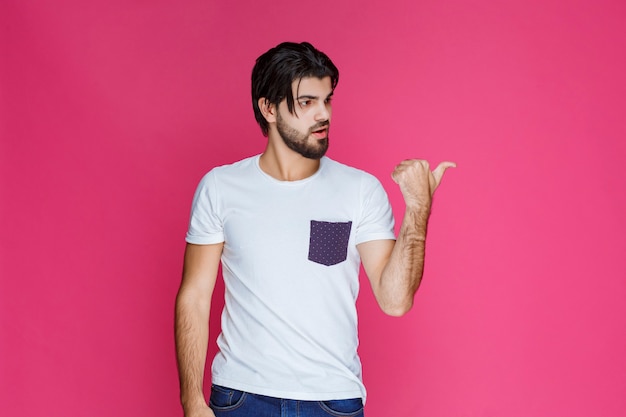 Man in white shirt making thumb up hand sign.