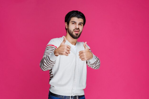 Uomo in una camicia bianca che fa il pollice sul segno.