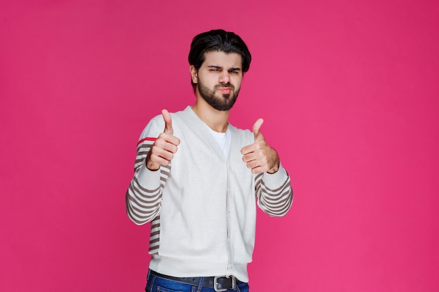 Man in a white shirt making thumb up sign. 