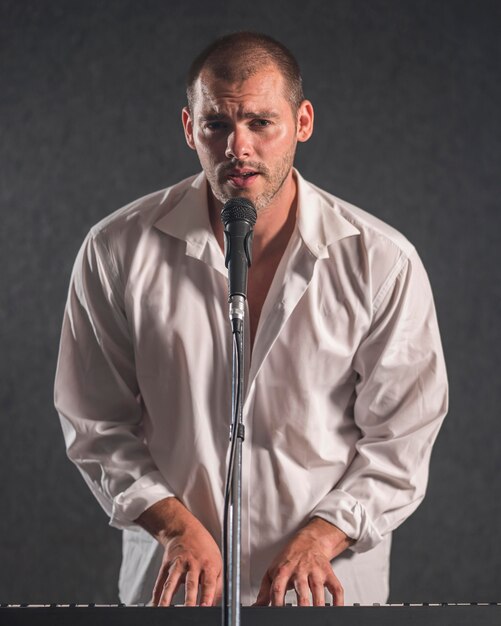 Man in white shirt playing digital piano and sings