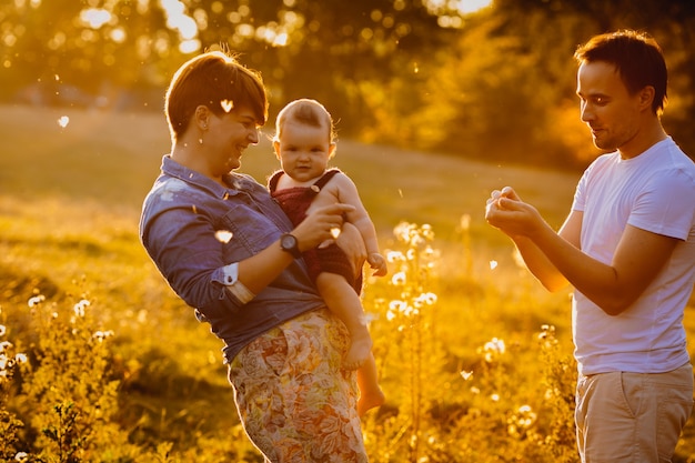 Man in white shirt plays with woman and child among the flowers 