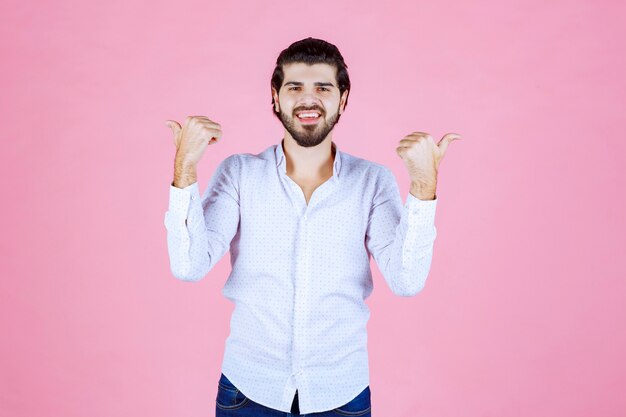 Man in a white shirt pointing backwards.