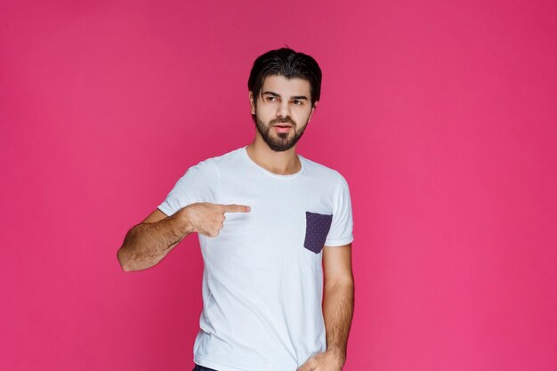 Man in white shirt pointing at himself. 