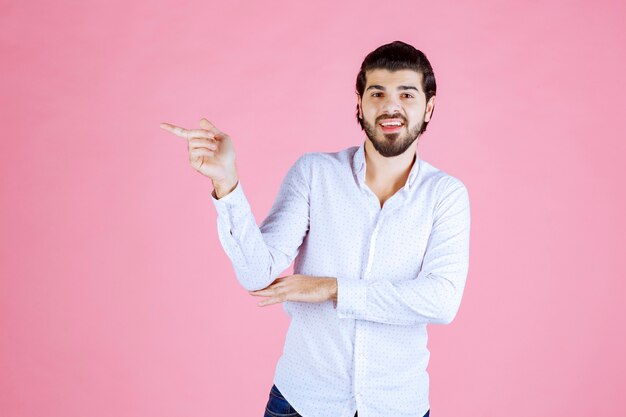 左側を指している白いシャツを着た男。