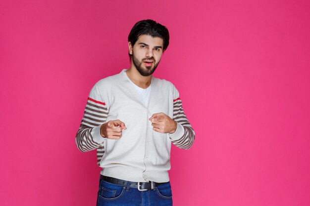 Man in white shirt pointing and presenting someone ahead. 