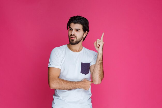 Man in white shirt pointing and presenting something above his head.