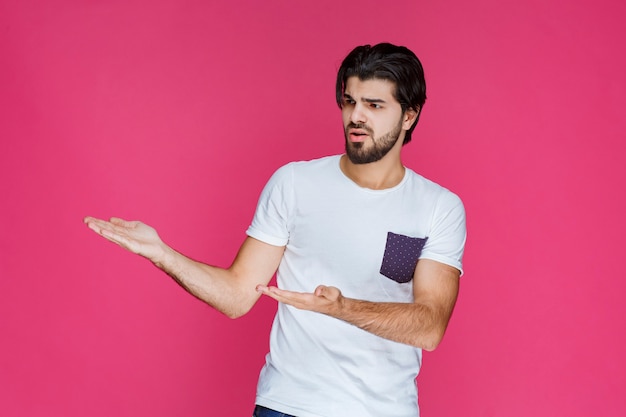 Man in white shirt pointing and presenting something on the left side.