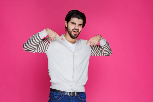 Man in white shirt pointing and presenting someting below his head. 