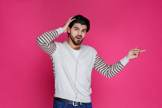 Uomo in camicia bianca che indica e che presenta qualcosa nella parte di destra.