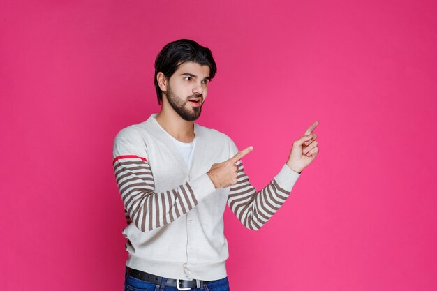 Man in white shirt pointing and presenting someting in the right side. 