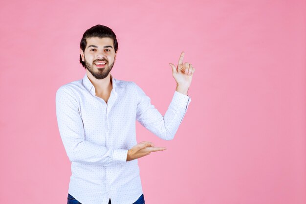 右側を指している白いシャツを着た男。