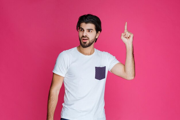 Man in white shirt pointing to something above. 