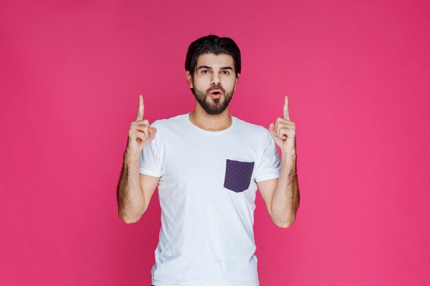 Man in white shirt pointing to something above. 