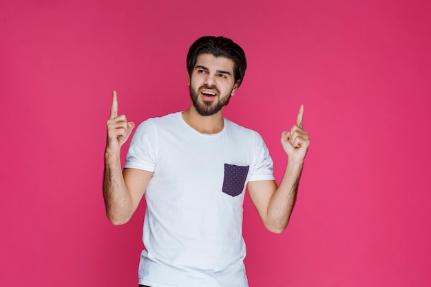 Man in white shirt pointing to something above. 