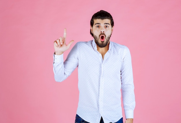 Man in a white shirt pointing at something above.