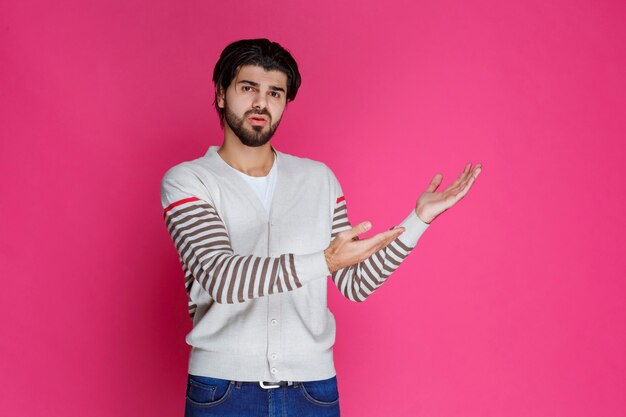 Man in white shirt pointing to somewhere and introducing someone or just showing the direction. 