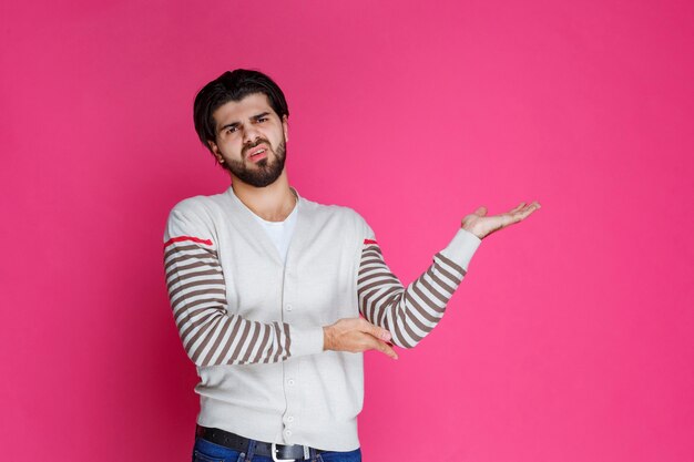 Man in white shirt pointing to somewhere and introducing someone or just showing the direction. 