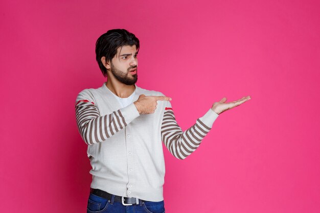 Man in white shirt pointing to somewhere and introducing someone or just showing the direction. 