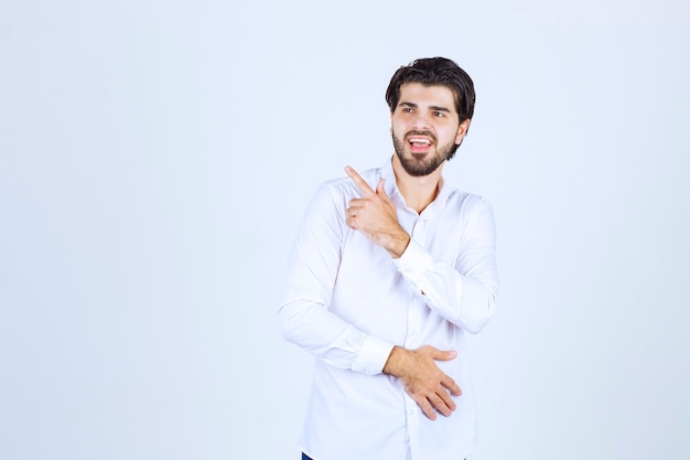 Man in white shirt pointing somewhere on the left with face emotions.