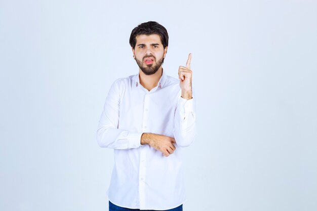 Man in white shirt pointing upside.