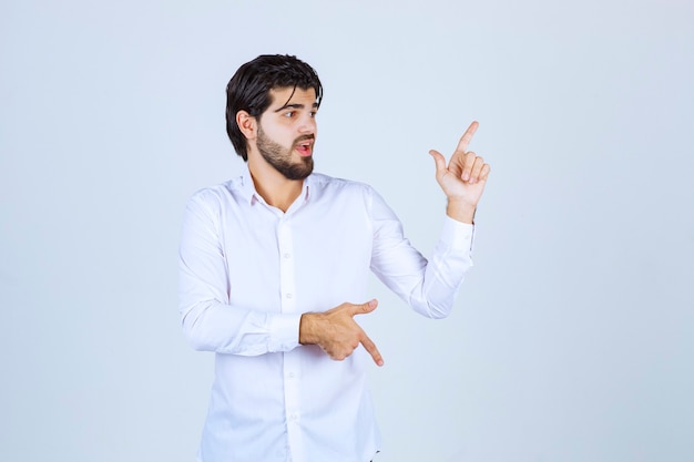 Man in white shirt pointing upside.