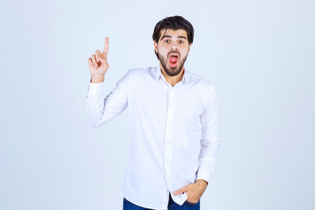 Man in white shirt pointing upside.