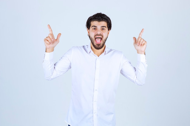 Free photo man in white shirt pointing upside.