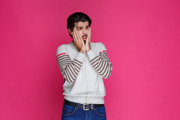 Man in white shirt puts his hands on himself and looks surprized and excited. 