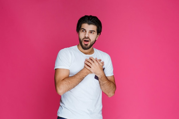 Free photo man in white shirt puts his hands on himself and looks surprized and excited.