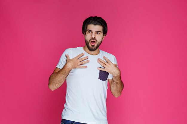 Man in white shirt puts his hands on himself and looks surprized and excited.