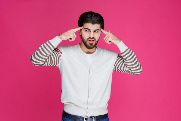 Man in white shirt putting hand to his head like he is thinking deep and trying to remember