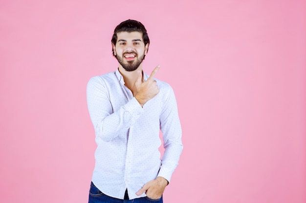 Free photo man in a white shirt raising his hand up to get attention or show something.