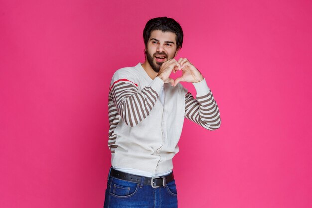 Man in a white shirt sending love to fans. 