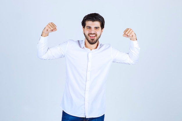 Man in white shirt showing his arm muscles and fist.