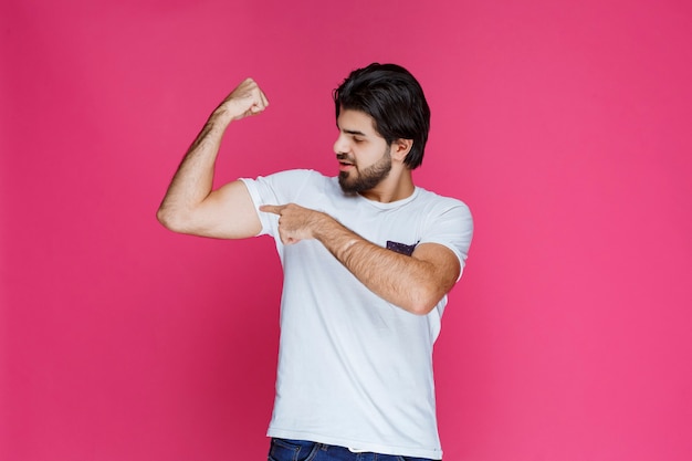 Man in white shirt showing his fist and biceps muscles.