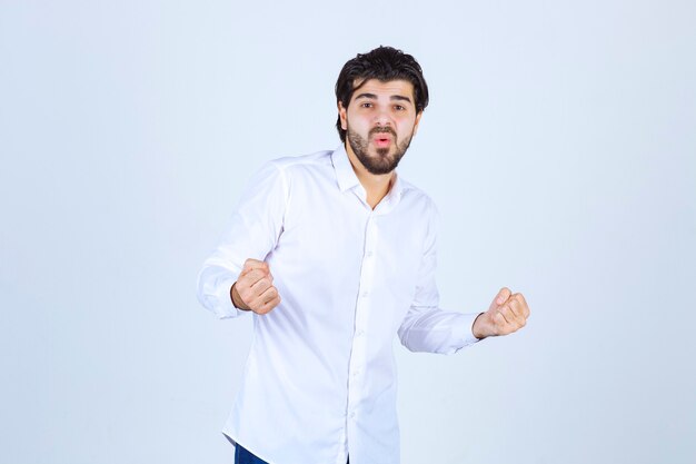 Man in white shirt showing his fists and feeling successful