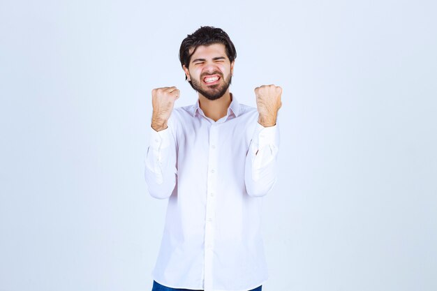 Man in white shirt showing his fists and feeling successful