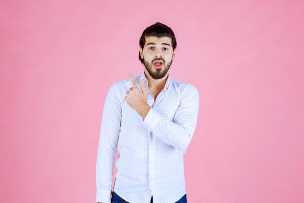 Man in a white shirt showing something behind.