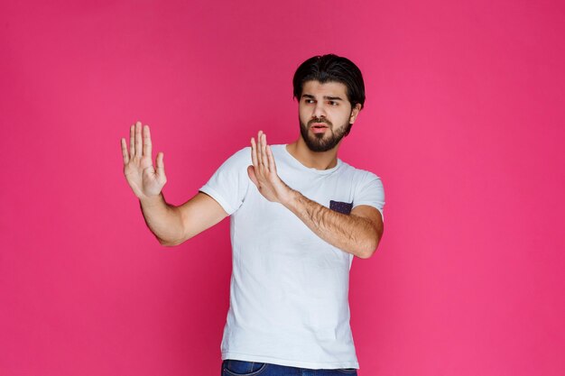 Man in white shirt stopping or preventing something. 