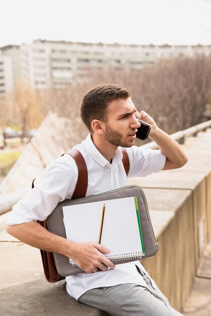 Man in white shirt talking on phone and looking away