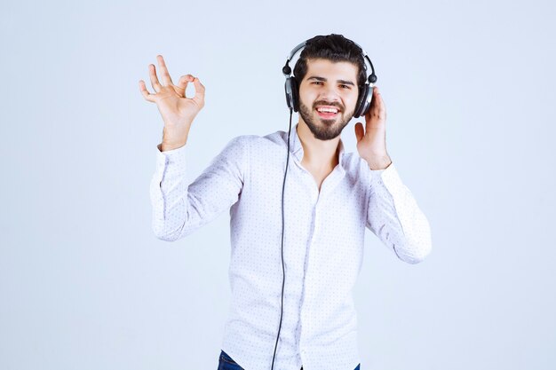 Man in white shirt wearing headphones and enjoying the music