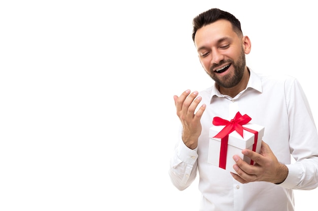 A man in a white shirt who received a gift rejoices unfolding it Premium Photo
