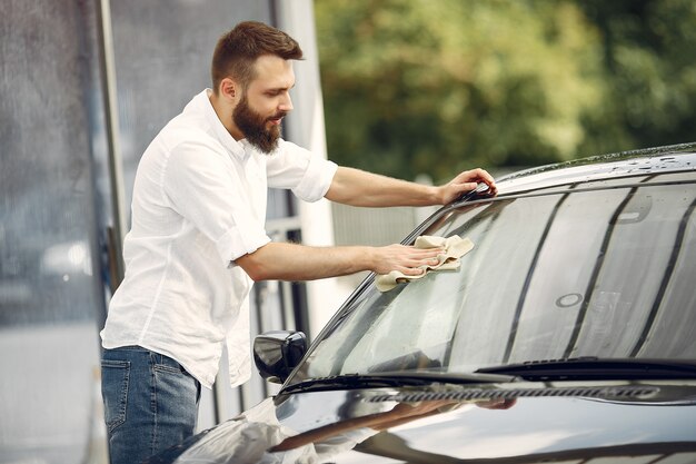 白いシャツを着た男が洗車で車を拭く