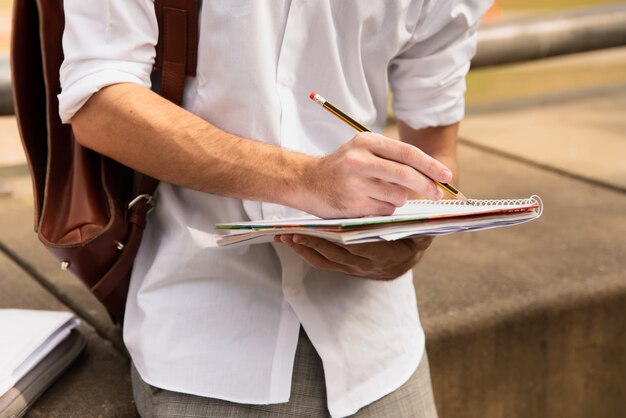 Man in white shirt writing with pencil on paper