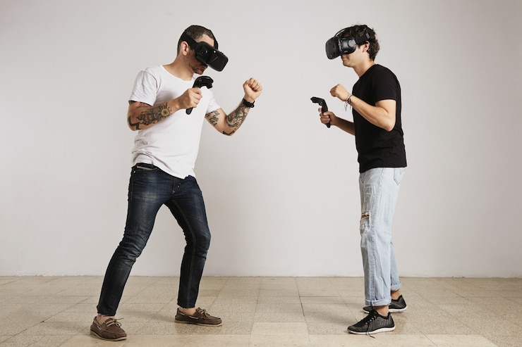 मुफ़्त फोटो a man in white unlabeled t-shirt with bear and tattoos and a man in black unlabeled t-shirt wearing vr headsets fight in a room with white walls.