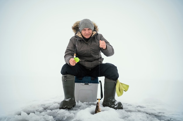 Free photo man in winter clothes fishing alone outside