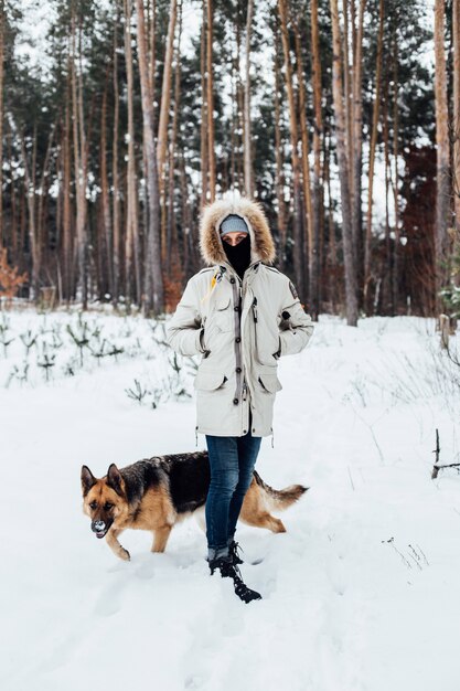 Man in winter coat in forest with shepherd dog