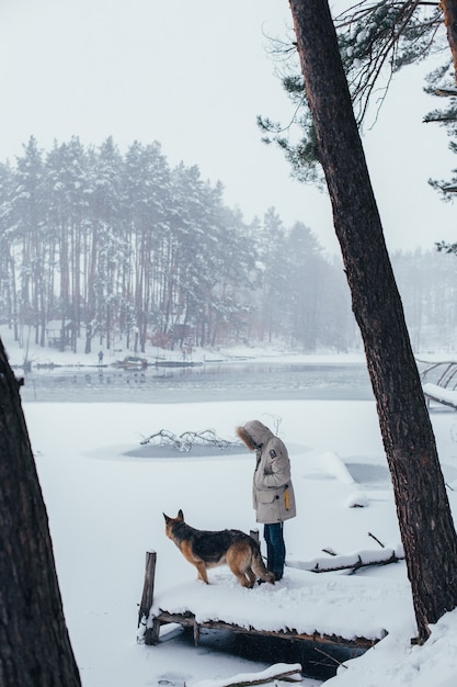 Foto gratuita uomo in cappotto invernale nella foresta con cane da pastore